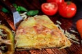 Close-up pizza slice with ham, salami and mozzarella cheese on wooden traditional background surrounded by fresh vegetables Royalty Free Stock Photo