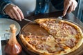 Close up on pizza on the wooden board on the table one piece missing hands of unknown person taking slice to eat Royalty Free Stock Photo