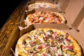 Close up of pizzas with variety of toppings and cheese in cardboard take out boxes Royalty Free Stock Photo