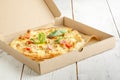 Close up of pizzas with variety of toppings and cheese in cardboard take out boxes with open lid on wooden table Royalty Free Stock Photo