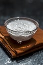 Close up of plain curd or yogurt or dahi in transparent glass bowl on a brown cloth or napkin on wooden surface. Royalty Free Stock Photo