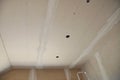 Close-up on plastering, skim coating, finishing a drywall ceiling and walls with cut holes for electrical wires with a paper Royalty Free Stock Photo