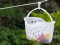 Close up of a plastic peg basket hanging from a washing line with water drops on Royalty Free Stock Photo