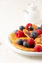 Close-up of plate of caramel pancakes with blueberries and raspberries with jar, on white table, selective focus Royalty Free Stock Photo