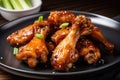 Close-up of a plate of crispy chicken teriyaki wings, hot and fresh out of the oven, served with a side of dipping sauce