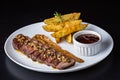 Close-up of a plate of food, containing a piece of grilled meat and a side of golden french fries Royalty Free Stock Photo