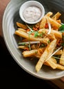 A close-up of a plate of french fries and a small container of dipping sauce on a wooden table Royalty Free Stock Photo