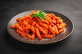 Close-up of a plate of freshly cooked Penne all`Arrabbiata pasta on a dark background