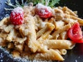 Close-up of a plate with pasta with sauce and parmesan cheese on a black plate in a restaurant