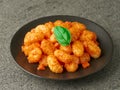 Close-up of a plate of POTATO GNOCCHI with tomato sauce on a gray stone background