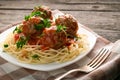 Close up plate of spaghetti with meatballs in tomato sauce sprinkled with parsley on table-napkin on wooden rustic table Royalty Free Stock Photo