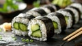 Close-up of a plate of sushi rolls with fresh cucumbers and chopsticks on the side