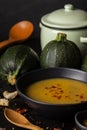 Close-up of plate of zucchini puree with paprika, round zucchini, stew, wooden spoon and garlic