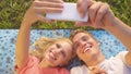 CLOSE UP: Playful young couple lying on a comfy blanket and taking selfies. Royalty Free Stock Photo