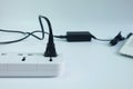 Close up plug in Adapter power cord charger with blurred laptop computer on white Royalty Free Stock Photo