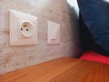 Close up of plug and light switch on bedroom wall. Wall switch to turn lights on and off. Electricity and home automation