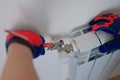 Plumber in protective gloves installing heating radiator in apartment or house