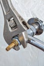 Close-up plumbers adjustable wrench tightens valve faucet. Royalty Free Stock Photo