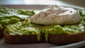 Close up of a poached egg on a smashed avocado toast with ground black pepper.