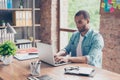 Close up of ponder young african handsome man. He is wearing casual smart, sitting at the workplace, looking in the laptop screen, Royalty Free Stock Photo