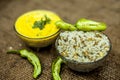 Close up of popular Indian & Asian lunch dish on brown colored surface i.e. Kadhi or Karhi and kichdi or chawal with fresh green