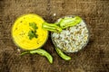 Close up of popular Indian & Asian lunch dish on brown colored surface i.e. Kadhi or Karhi and kichdi or chawal with fresh green