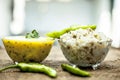 Close up of popular Indian & Asian lunch dish on brown colored surface i.e. Kadhi or Karhi and kichdi or chawal with fresh green