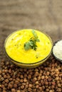 Close up of popular Indian & Asian lunch dish on brown colored surface i.e. Kadhi or Karhi and kichdi with raw cickpeas and besan