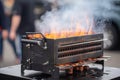 close-up of portable grill, with smoke and flames visible