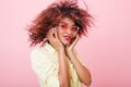 Close-up portrait of adorable mulatto girl in pink sunglasses touching earphones during photoshoot. Indoor photo of