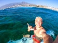 Close up and portrait of adult man enjoying summer in vacations taking a selfie in the sea or ocean at the beach with his Royalty Free Stock Photo