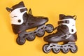 Close up portrait of adult rolling skates isolated over yellow studio background, white and black roller skates, image of pair of