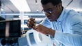Close Up Portrait of an African American Robotics Engineer Setting Up a Robot Dog Prototype, Using a Royalty Free Stock Photo
