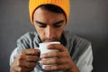 Close-up portrait of alone sitting young handsome man with a mug of coffee, tea, water, on gray background. Royalty Free Stock Photo