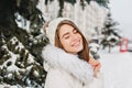 Close up portrait of amazing joyful girl in white warm warm clothes enjoying winter time in city. Young pretty woman in