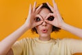 Close-up portrait of amazing pale girl making funny faces on yellow background. Photo of funny white woman with short