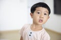 Close-up portrait Asian child boy straight black hair wearing a light brown shirt looking at camera of him make funny faces of Royalty Free Stock Photo