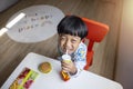 Close-up portrait Asian child boy straight black hair wearing a white pajamas with blue stripes looking at camera of him make Royalty Free Stock Photo