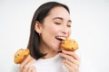Close up portrait of asian girl eats cupcakes with happy face, isolated on white background Royalty Free Stock Photo