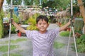 Close-up portrait of Asian little boy child spread arms out and hold tight onto the rope while standing on swing in the garden Royalty Free Stock Photo