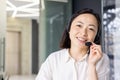 Close-up portrait of Asian online support worker, woman smiling and looking at camera using headset phone for online Royalty Free Stock Photo