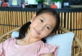 Close up portrait of Asian young girl child age about 9 years old lying on chair and looking camera Royalty Free Stock Photo