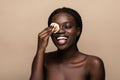 Close up portrait of an attractive african american woman removing makeup with sponge isolated on beige background Royalty Free Stock Photo