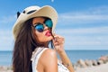 Close-up portrait of attractive brunette girl with long hair standing on the beach near sea. She wears hat, sunglasses Royalty Free Stock Photo