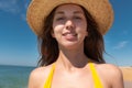 Close-up portrait of attractive caucasian young woman in straw hat and yellow swimsuit smiling against blue sky and sea Royalty Free Stock Photo