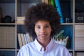 Close-up portrait of attractive dark skinned young woman with curly Afro hairstyle. African american businesswoman at office Royalty Free Stock Photo