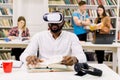 Close up portrait of attractive focused young african american bearded student sitting in library and reading book in vr Royalty Free Stock Photo