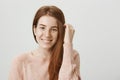 Close-up portrait of attractive ginger girl with freckles touching hair while smiling broadly and glancing at camera Royalty Free Stock Photo