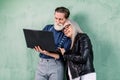 Close up portrait of attractive happy stylish senior couple, man and woman, leaning on green wall and embracing each Royalty Free Stock Photo