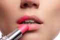Close up portrait of attractive lips of beautiful woman. Rouging her lips with pink mate lipstick. The lady is gently smiling. Clo Royalty Free Stock Photo